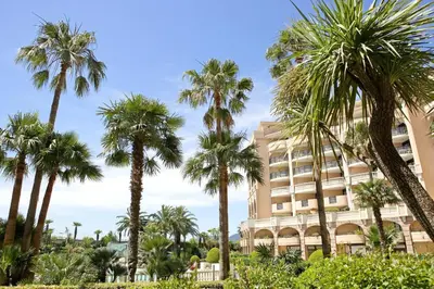 a building with palm trees in front of it at Appartement Vue Mer Cannes Azur in Cannes