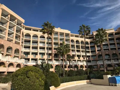 a large building with palm trees in front of it at Appartement Vue Mer Cannes Azur in Cannes