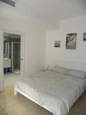a white bedroom with a bed and a bathroom at Secret Garden in Cannes