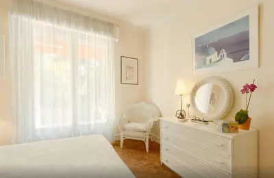 a bedroom with a bed and a dresser and a window at Cannes Film Festival Beach Apartment in Cannes