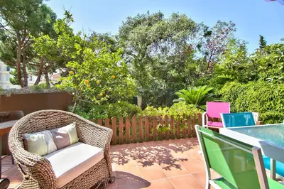 a wicker chair sitting on a patio with a laptop at Cannes Film Festival Beach Apartment in Cannes