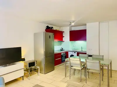 a kitchen with red cabinets and a table and chairs at Très Joli T3 Vieux Port Cannes in Cannes