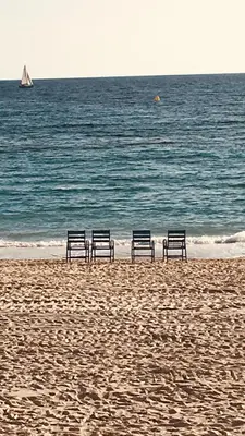 three benches sitting on a beach near the water at Touchlux apartments in Cannes