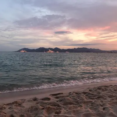 a beach with the ocean and mountains in the background at Touchlux apartments in Cannes