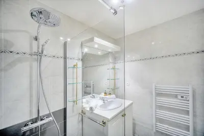 a white bathroom with a sink and a shower at IMMOGROOM - Sea view - Swimming Pool - Terrace- Clim in Cannes