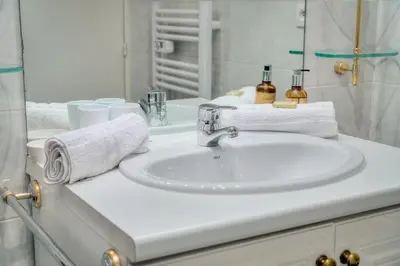 a white bathroom sink with towels and a mirror at IMMOGROOM - Sea view - Swimming Pool - Terrace- Clim in Cannes