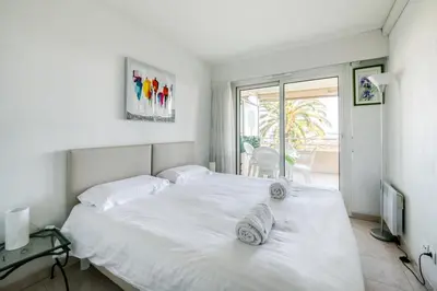 a bedroom with a white bed and a balcony at IMMOGROOM - Sea view - Swimming Pool - Terrace- Clim in Cannes