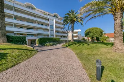 a walkway in front of a building with palm trees at IMMOGROOM - Sea view - Swimming Pool - Terrace- Clim in Cannes