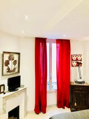 a bedroom with red curtains in front of a window at Apartment 3 Pieces in Cannes