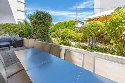 a beach with people sitting on the sand and the water at Apartment 2 bedrooms2 bathroomsdouble terrace & Garden in Palm beach area in Cannes