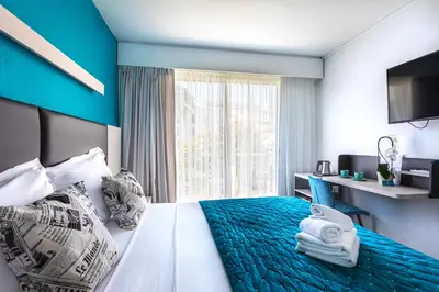 a hotel room with a bed and a window at Hôtel Jardin Croisette in Cannes