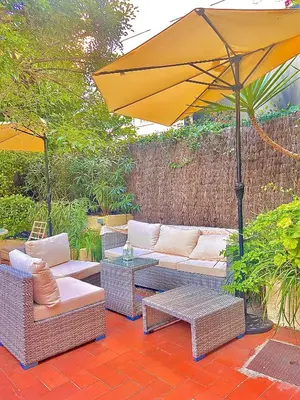 a patio with a couch and an umbrella at Hôtel Jardin Croisette in Cannes