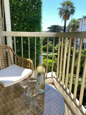 a bottle of wine sitting on a table on a balcony at Hôtel Jardin Croisette in Cannes