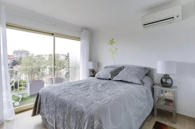 a white bedroom with a bed and a large window at IMMOGROOM - Apartment with terrace - AC - Parking in Cannes