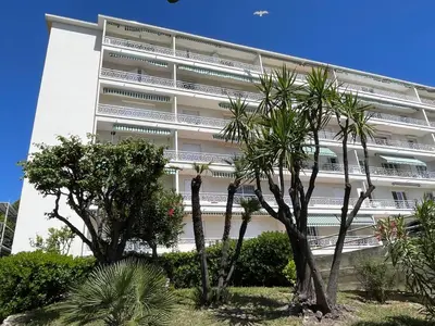 a white building with palm trees in front of it at VUE MER - Appartement T2 in Cannes
