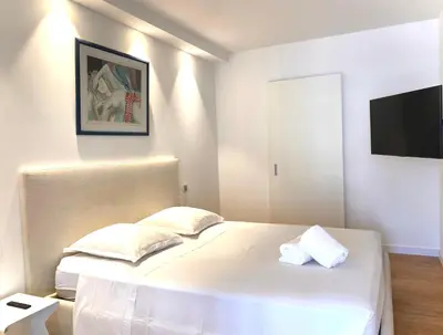 a bedroom with a white bed and a flat screen tv at Grand 2 pieces Gray d'Albion in Cannes