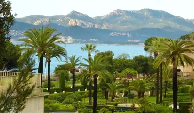 a view of a park with palm trees and a lake at Appartement moderne à Cannes avec vue sur mer et montagne - 85 m² in Cannes
