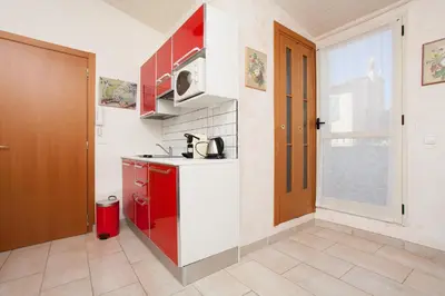 a small kitchen with red cabinets and a red door at Frères Suquet Sea Cannes in Cannes