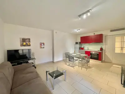 a living room with a couch and a kitchen with red cabinets at Le Vieux Port Apartments in Cannes