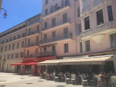 a group of people sitting at tables in front of a building at Le Vieux Port Apartments in Cannes