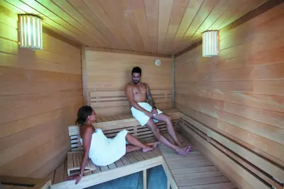 a man and woman sitting in a sauna at Cristal Hôtel & Spa in Cannes