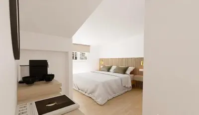a white bedroom with a bed and a television at Hotel le Romanesque in Cannes