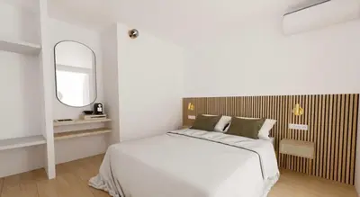 a white bedroom with a bed and a mirror at Hotel le Romanesque in Cannes