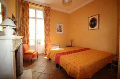 a bedroom with a bed and a chair and a window at AGENCIA appartement Rue d'Antibes in Cannes
