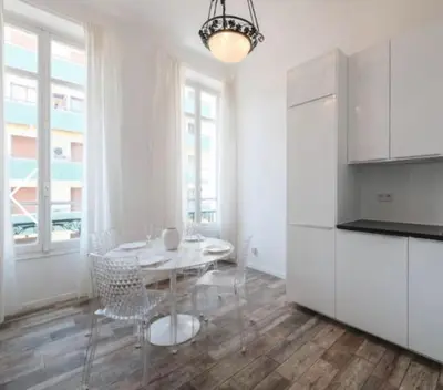 a white kitchen with a table and a refrigerator at Ice coeur de Cannes in Cannes