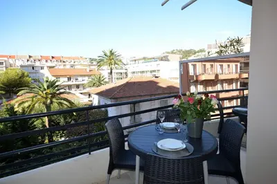 a table on a balcony with a view of a city at Palais Rouaze Cannes in Cannes