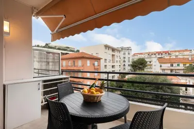 a table and chairs on a balcony with a bowl of fruit at Palais Rouaze Cannes in Cannes