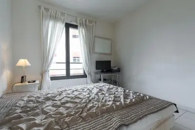 a white bedroom with a large bed and a window at Appartement de charme à Cannes + terrasse in Cannes