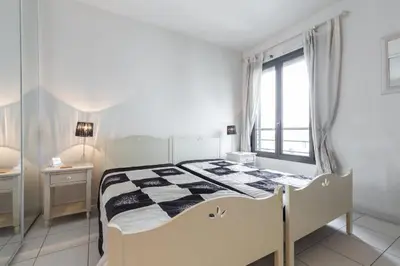 a white bedroom with a bed and a window at Appartement de charme à Cannes + terrasse in Cannes