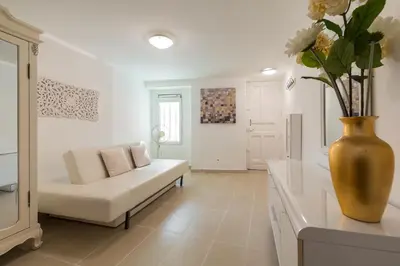 a white bedroom with a bed and a chair at A lovely split level townhouse in the heart of Cannes next to the Marche Forville and the Palais 1749 in Cannes