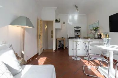 a white bedroom with a bed and a chair at A lovely split level townhouse in the heart of Cannes next to the Marche Forville and the Palais 1749 in Cannes