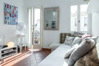 a living room with a white bed and a kitchen at A lovely split level townhouse in the heart of Cannes next to the Marche Forville and the Palais 1749 in Cannes