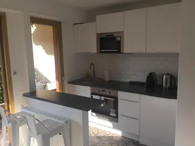 a kitchen with white cabinets and a black counter top at Amazing Studio Cannes Center - Terrassse - 5 min Croisette in Cannes