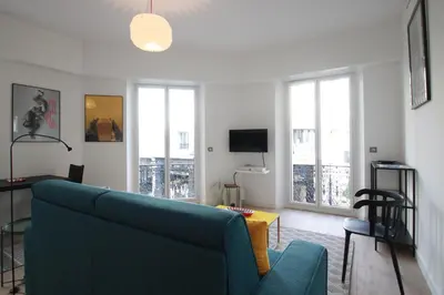 a living room with a blue couch and a tv at Palais Foch in Cannes