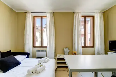 a room with a bed and a table and windows at IMMOGROOM - Historic Area Le Suquet - 6min from the beaches in Cannes