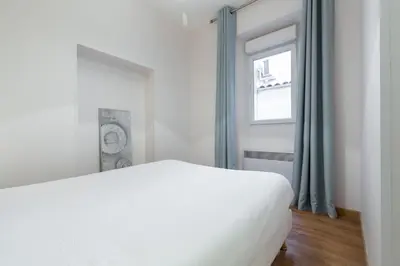 a white bed in a room with a window at Florella Clemenceau Apartment in Cannes