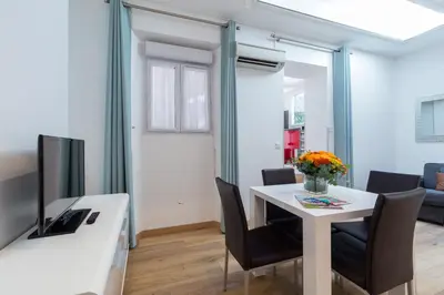 a dining room with a white table and a tv at Florella Clemenceau Apartment in Cannes
