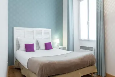 a bedroom with a large white bed with purple pillows at Florella Clemenceau Apartment in Cannes