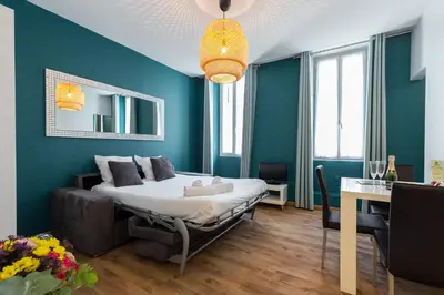 a bedroom with a bed with blue walls and a table at Florella Clemenceau Apartment in Cannes
