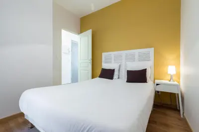 a bedroom with a white bed and a yellow wall at Florella Clemenceau Apartment in Cannes