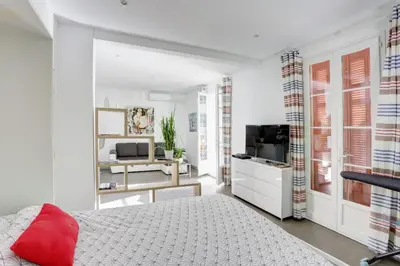a white bedroom with a red pillow on a bed at Appartements Cannes in Cannes
