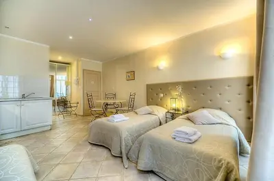 a bedroom with two beds and a kitchen with a table at Residence Chryseis in Cannes