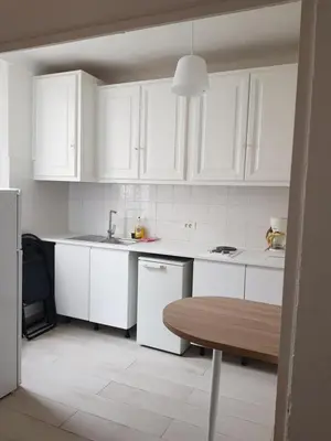 a kitchen with white cabinets and a wooden table at Residence Chryseis in Cannes