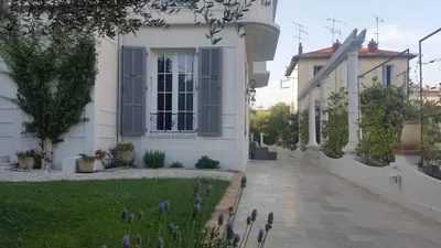 a white house with purple flowers in the yard at B&B Villa Blanche in Cannes