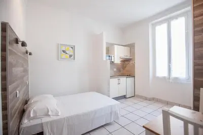 a white room with a bed and a kitchen at Appartements Foch in Cannes
