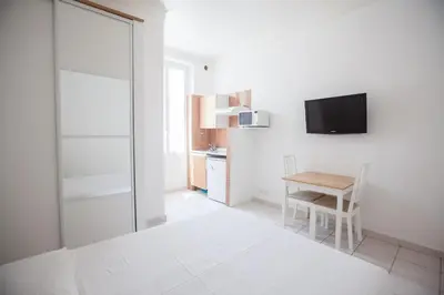a white room with a table and a tv on a wall at Appartements Foch in Cannes